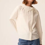 Modèle portant la blouse en popeline écru Soline DES PETITS HAUTS avec un jean bleu