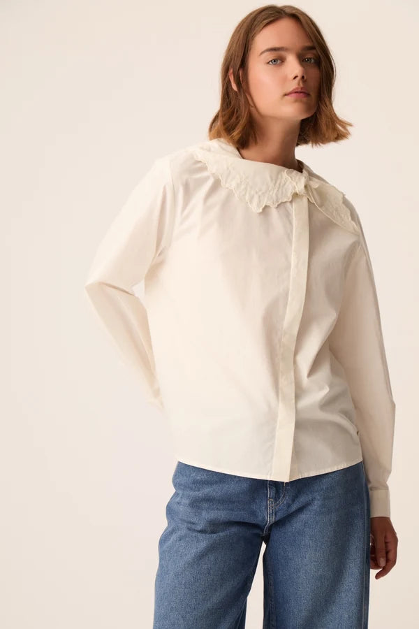 Modèle portant la blouse en popeline écru Soline DES PETITS HAUTS avec un jean bleu