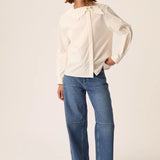 Vue d'ensemble du look avec la blouse asymétrique écru Soline DES PETITS HAUTS et un jean large et des sandales noires