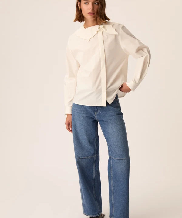 Vue d'ensemble du look avec la blouse asymétrique écru Soline DES PETITS HAUTS et un jean large et des sandales noires