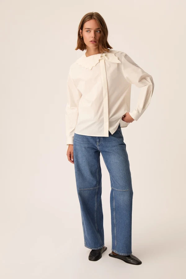 Vue d'ensemble du look avec la blouse asymétrique écru Soline DES PETITS HAUTS et un jean large et des sandales noires
