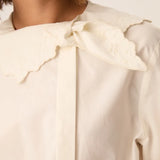 Gros plan sur les broderies, le nœud et la patte de boutonnage décalée de la blouse Soline DES PETITS HAUTS