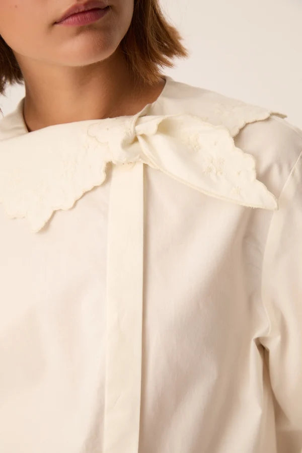 Gros plan sur les broderies, le nœud et la patte de boutonnage décalée de la blouse Soline DES PETITS HAUTS