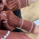 Gros plan sur les poignets fronces et brodes de la blouse bordeaux Viramette VILA