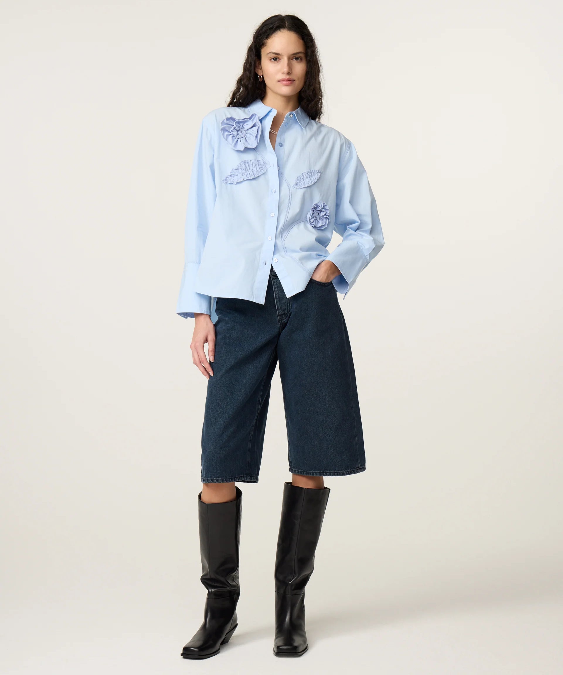 Vue en pied de la blouse ample bleu clair FABIENNE CHAPOT portée avec un bermuda en jean et des bottes hautes