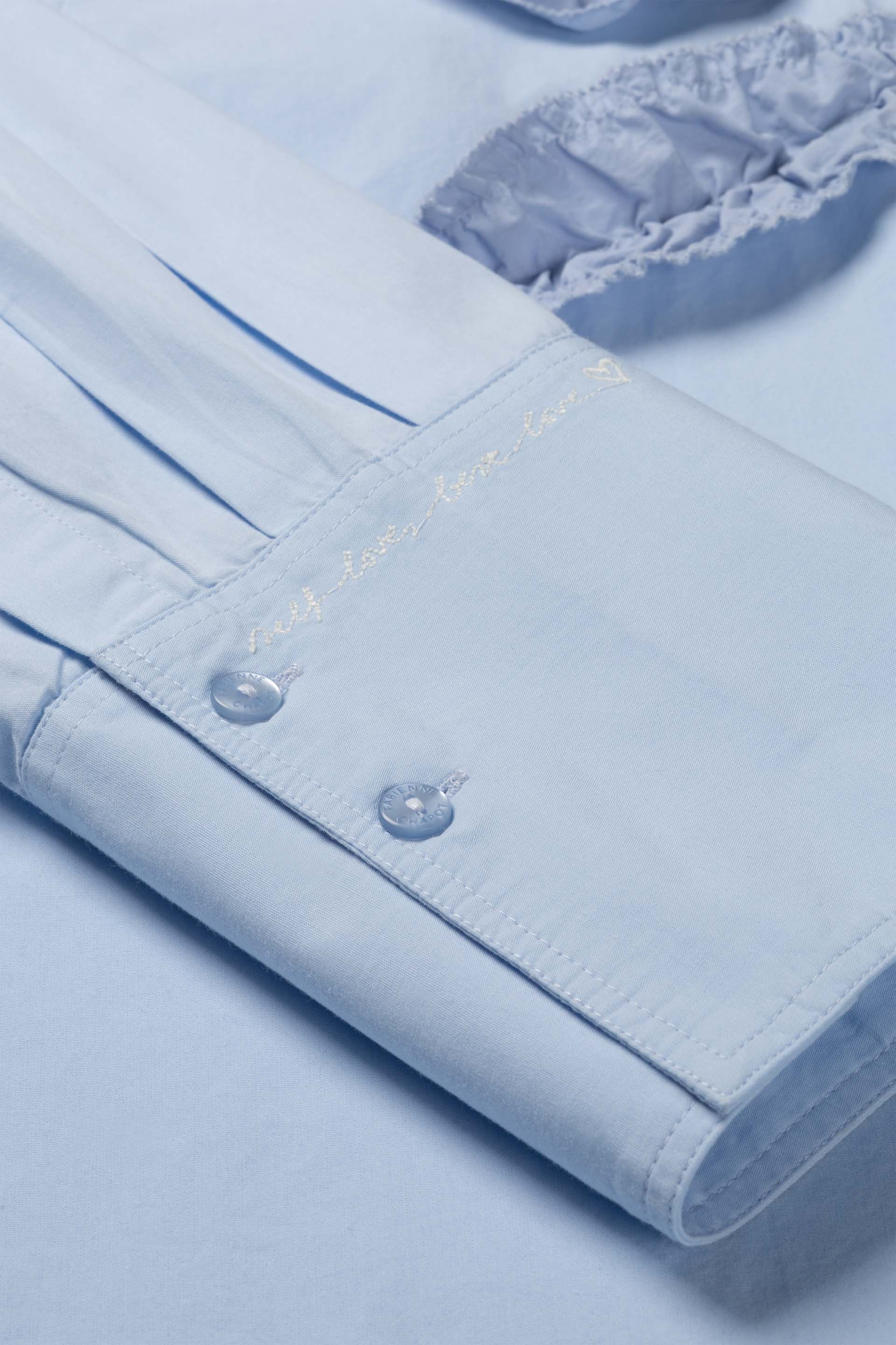 Gros plan sur les poignets larges structurés et le détail de broderie de la blouse FABIENNE CHAPOT