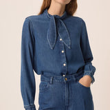 Vue de face de la blouse en denim fluide Lenora DES PETITS HAUTS avec col bandana à nouer et un jean