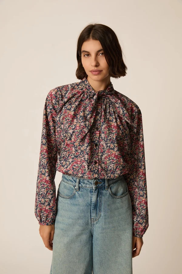 Modèle portant la blouse lavallière fleurie Rainbow Taya DES PETITS HAUTS avec un berrmuda en jean