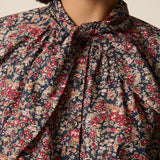 Zoom sur le nœud lavallière et le motif fleuri Liberty Taya bleu marine de la blouse Rainbow DES PETITS HAUTS
