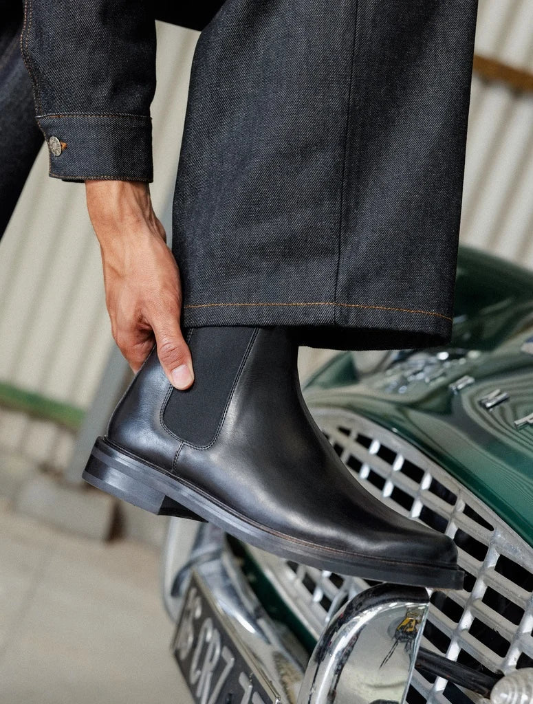 Visuel porté de profil des Chelsea boots en cuir lisse noir intense BOBBIES HOMME Grant avec un pantalon en jean