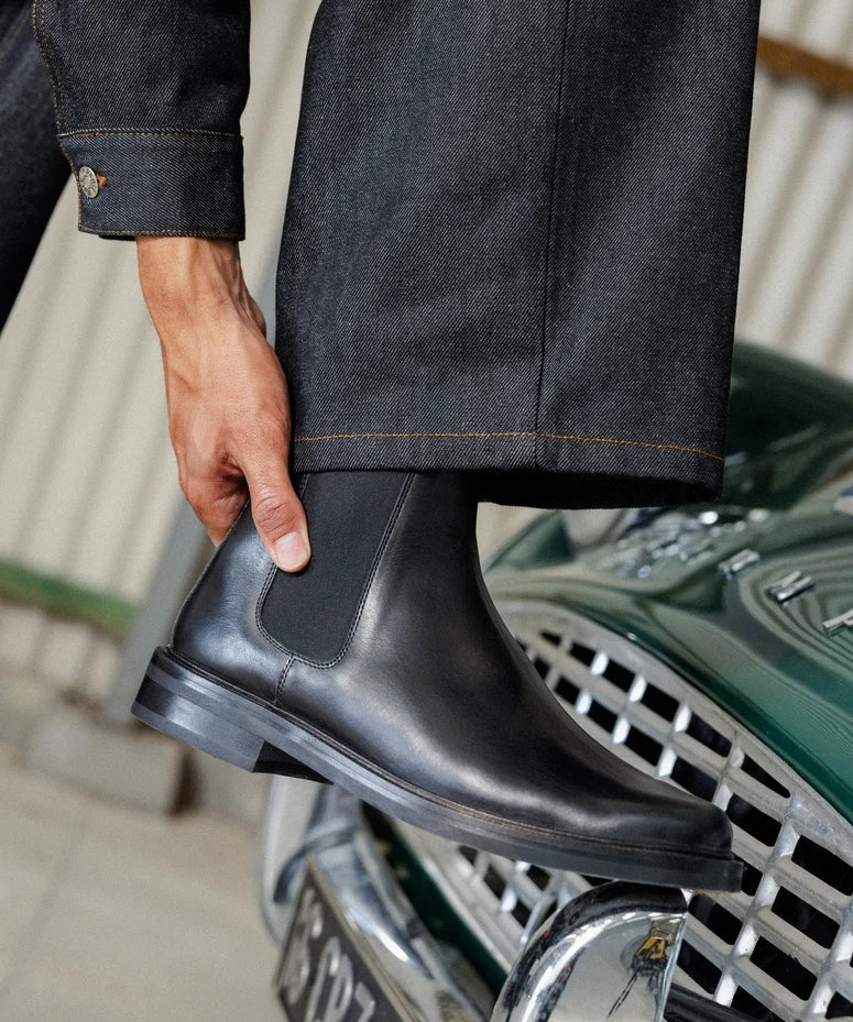Visuel porté de profil des Chelsea boots en cuir lisse noir intense BOBBIES HOMME Grant avec un pantalon en jean
