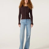 Silhouette complète portée avec le cardigan marron Lilo FABIENNE CHAPOT et un jean wide-leg bleu clair