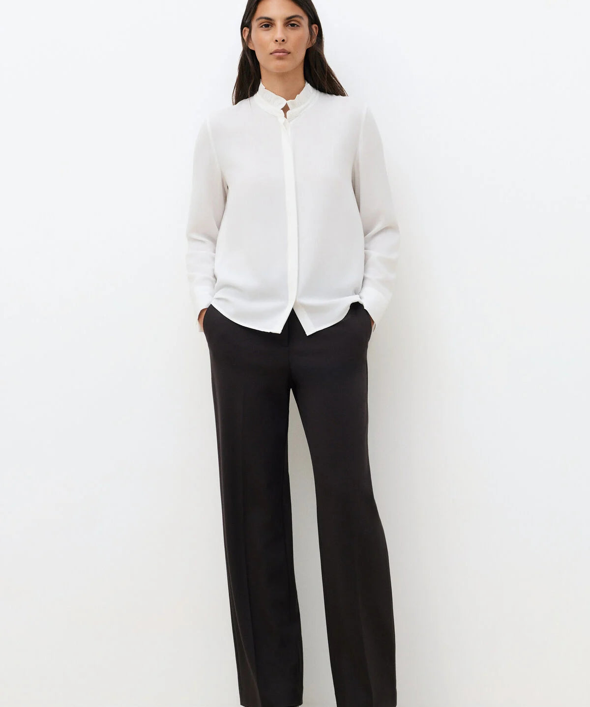 Silhouette complète avec la chemise blanche CAROLL Cira portée avec un pantalon de tailleur noir
