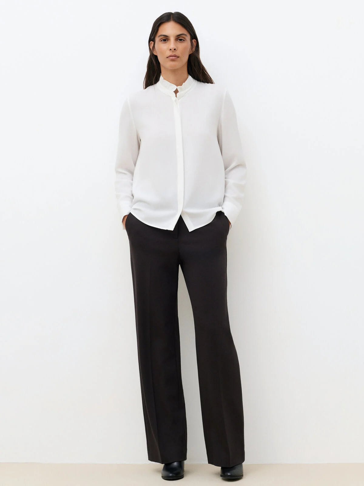Silhouette complète avec la chemise blanche CAROLL Cira portée avec un pantalon de tailleur noir