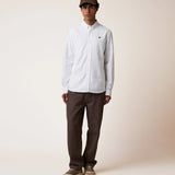 Chemise blanche homme Ivoy FAGUO avec un pantalon décontracté et casquette