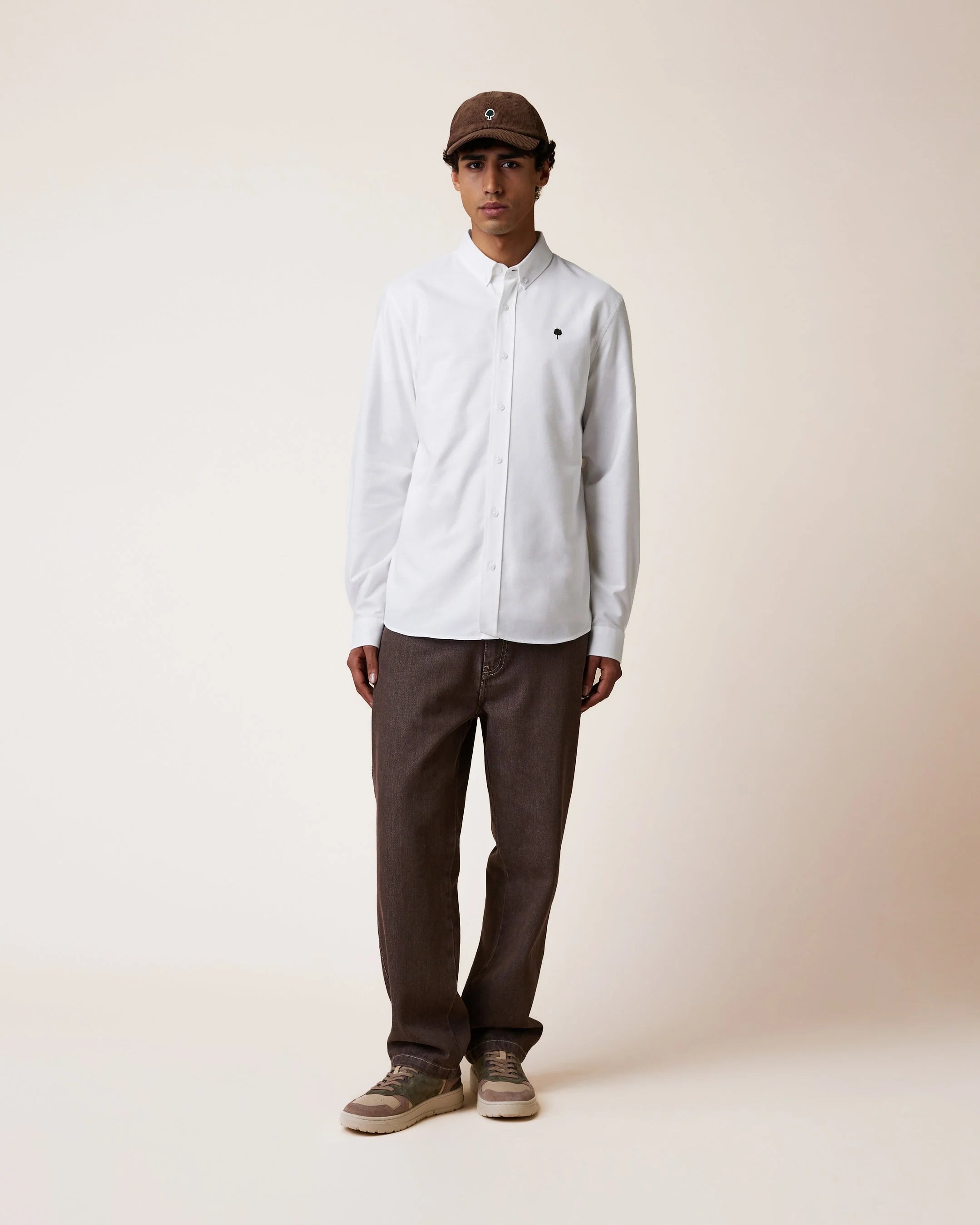 Chemise blanche homme Ivoy FAGUO avec un pantalon décontracté et casquette