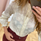 Gros plan sur la broderie florale, le col volanté et la patte de boutonnage de la blouse IN APRIL 1986