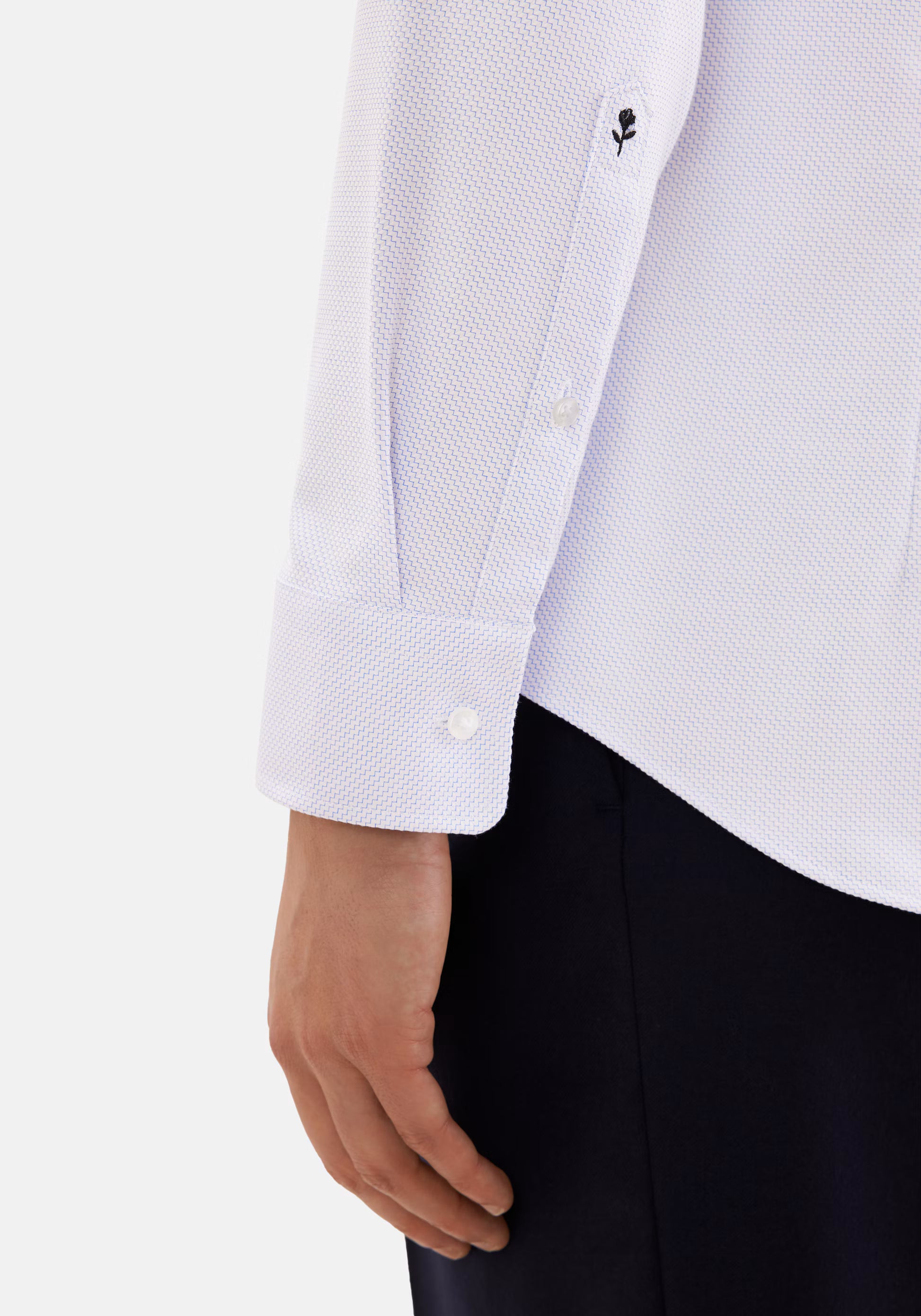 Zoom sur le poignet réglable et la broderie rose emblématique de la chemise SEIDENSTICKER