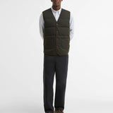 Vue en pied du look avec la doudoune sans manches sauge foncé Barbour, un pantalon droit et des chaussures en cuir marron