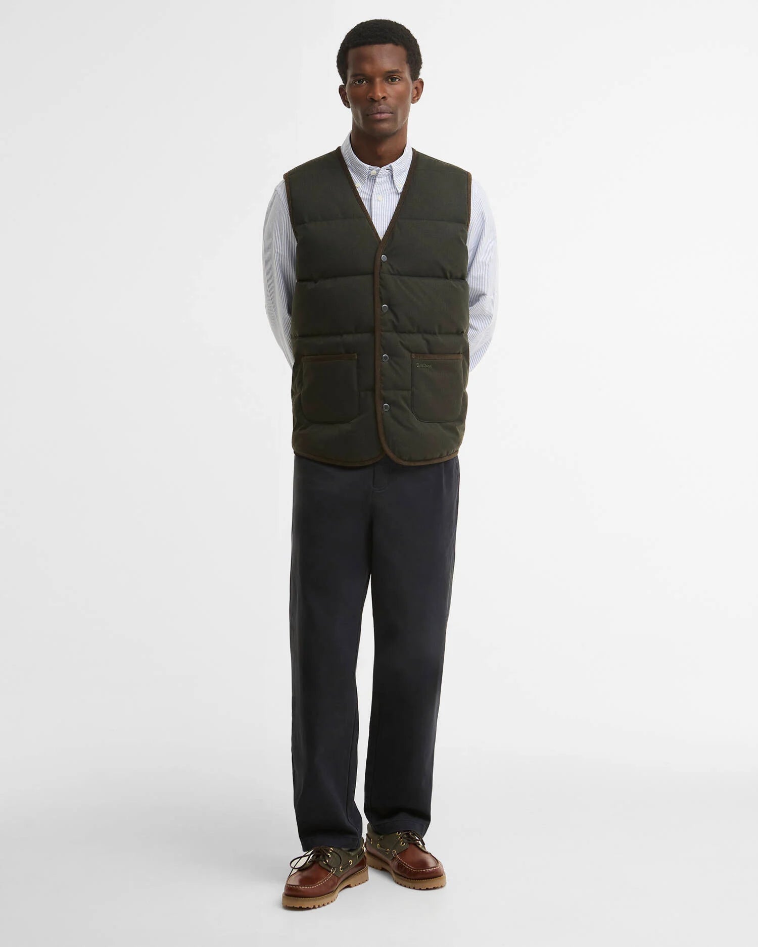 Vue en pied du look avec la doudoune sans manches sauge foncé Barbour, un pantalon droit et des chaussures en cuir marron