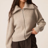 Modèle portant le gilet zippé Andrea gris galet DES PETITS HAUTS avec col ouvert et pantalon marron