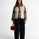 Look complet avec le gilet moumoute Bainford BARBOUR beige, surchemise à carreaux, pantalon large noir et sac rouge