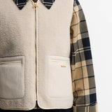 Gros plan sur la fermeture zippée en laiton, la texture moumoute et la poche en velours brodée Barbour