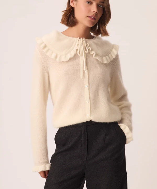 Modèle portant le gilet crème Carlie DES PETITS HAUTS à col Claudine volanté avec un pantalon sombre
