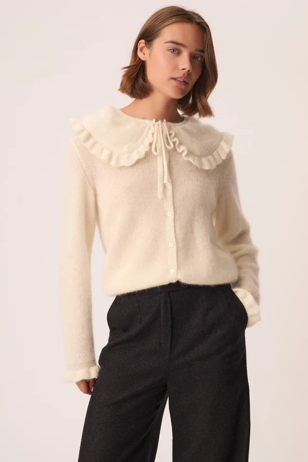 Modèle portant le gilet crème Carlie DES PETITS HAUTS à col Claudine volanté avec un pantalon sombre