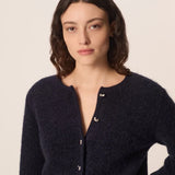 Modèle accroupi mettant en valeur la maille bouclée et les manches du gilet marine Cumin DES PETITS HAUTS