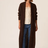 Modèle portant le gilet long marron foncé Aurore DES PETITS HAUTS avec jean brut et top écru