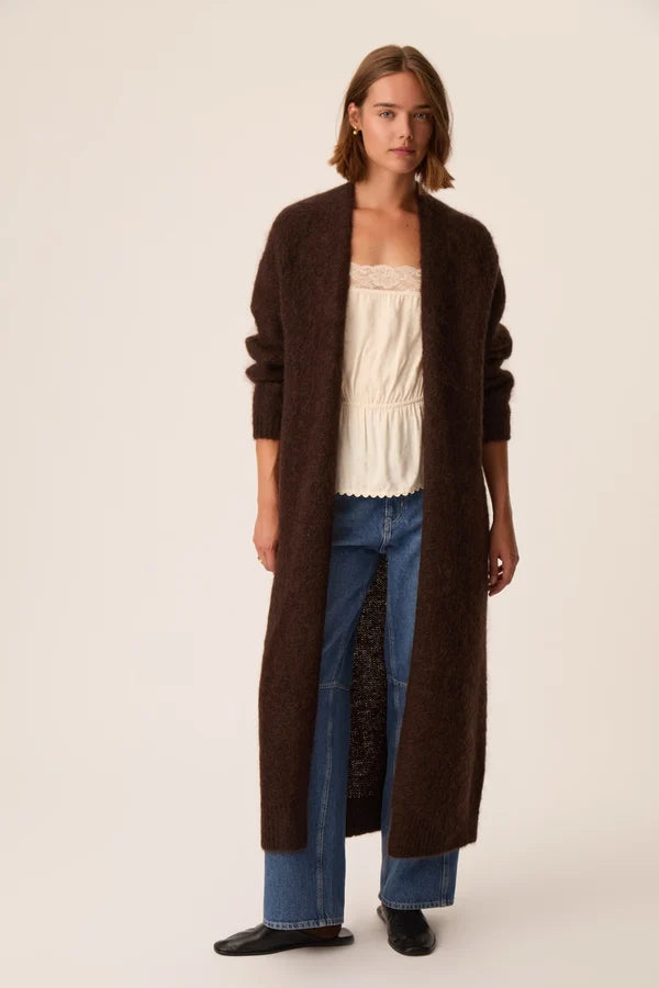 Modèle portant le gilet long marron foncé Aurore DES PETITS HAUTS avec jean brut et top écru