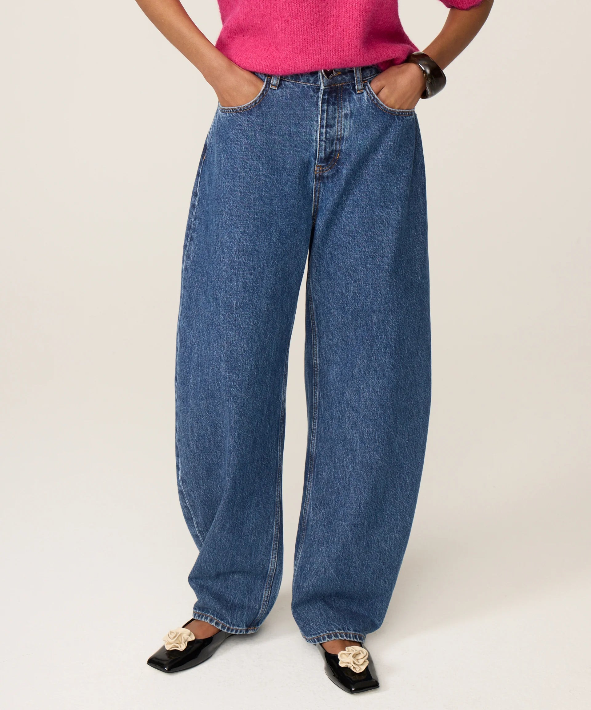 Visuel porté des jambes et des pieds du jean délavé bleu moyen FABIENNE CHAPOT Betty Barrel avec un pull rose