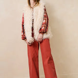 Vue d'ensemble du look avec le jean ample Gustol terracotta, gilet sans manche en fausse fourrure et chemise
