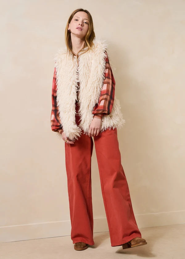 Vue d'ensemble du look avec le jean ample Gustol terracotta, gilet sans manche en fausse fourrure et chemise