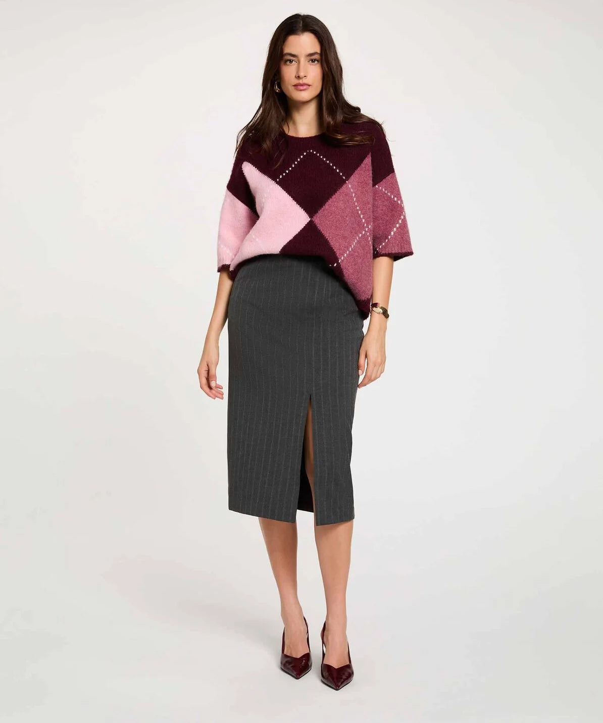 Vue de face d'un modèle portant la jupe crayon taille haute gris foncé MORGAN Jcosy fendue longueur 3/4 portée avec un pull ample en maille et des des escarpins