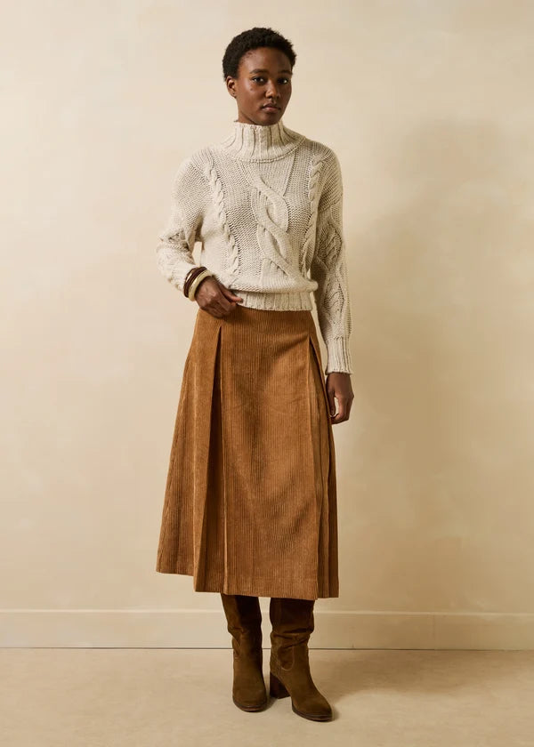 Silhouette complète portée avec la jupe velours cognac Genaro LA FÉE MARABOUTÉE, pull col montant écru et bottes suédées