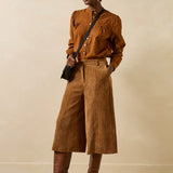 Silhouette complète portée avec le bermuda large cognac Galiope LA FÉE MARABOUTÉE, chemisier fluide et bottes à talons