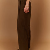 Vue de profil du pantalon large gris carbone SUNCOO Jovial avec une ceinture fine noire et un pull en maille rayé