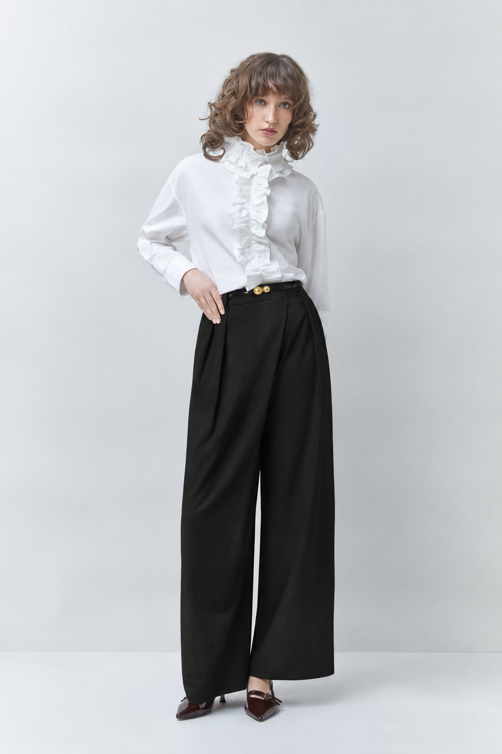 Silhouette complète du pantalon large noir SUNCOO FEMME Jupiter porté par un mannequin avec une chemise blanche à volants