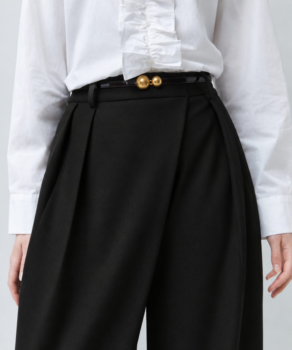 Zoom sur la taille haute et le drapé croisé du pantalon noir SUNCOO FEMME Jupiter porté avec une ceinture fine dorée