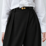Zoom sur la taille haute et le drapé croisé du pantalon noir SUNCOO FEMME Jupiter porté avec une ceinture fine dorée