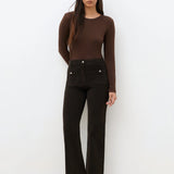 Pantalon bootcut en velours côtelé marron foncé CAROLL Pelley avec poches plaquées boutonnées porté avec un top marron et des bottines
