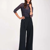 Pantalon large bleu marine MORGAN Pwrap à plis croisés porté de face avec un top ajusté à carreaux en transparence et des escarpins
