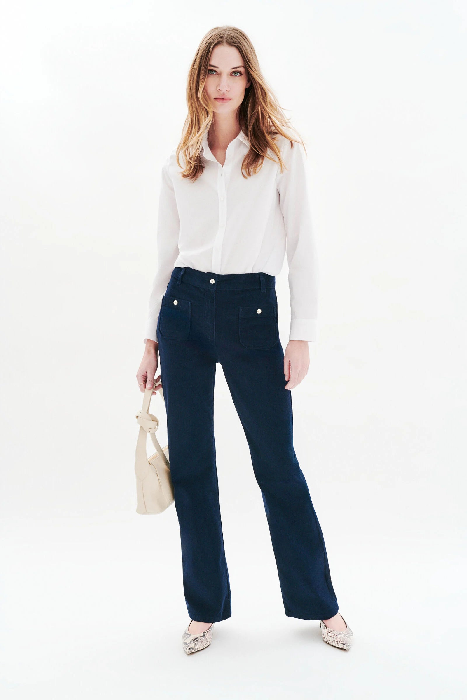 Vue de face du pantalon bootcut en velours marine CAROLL Pelley porté avec des escarpins