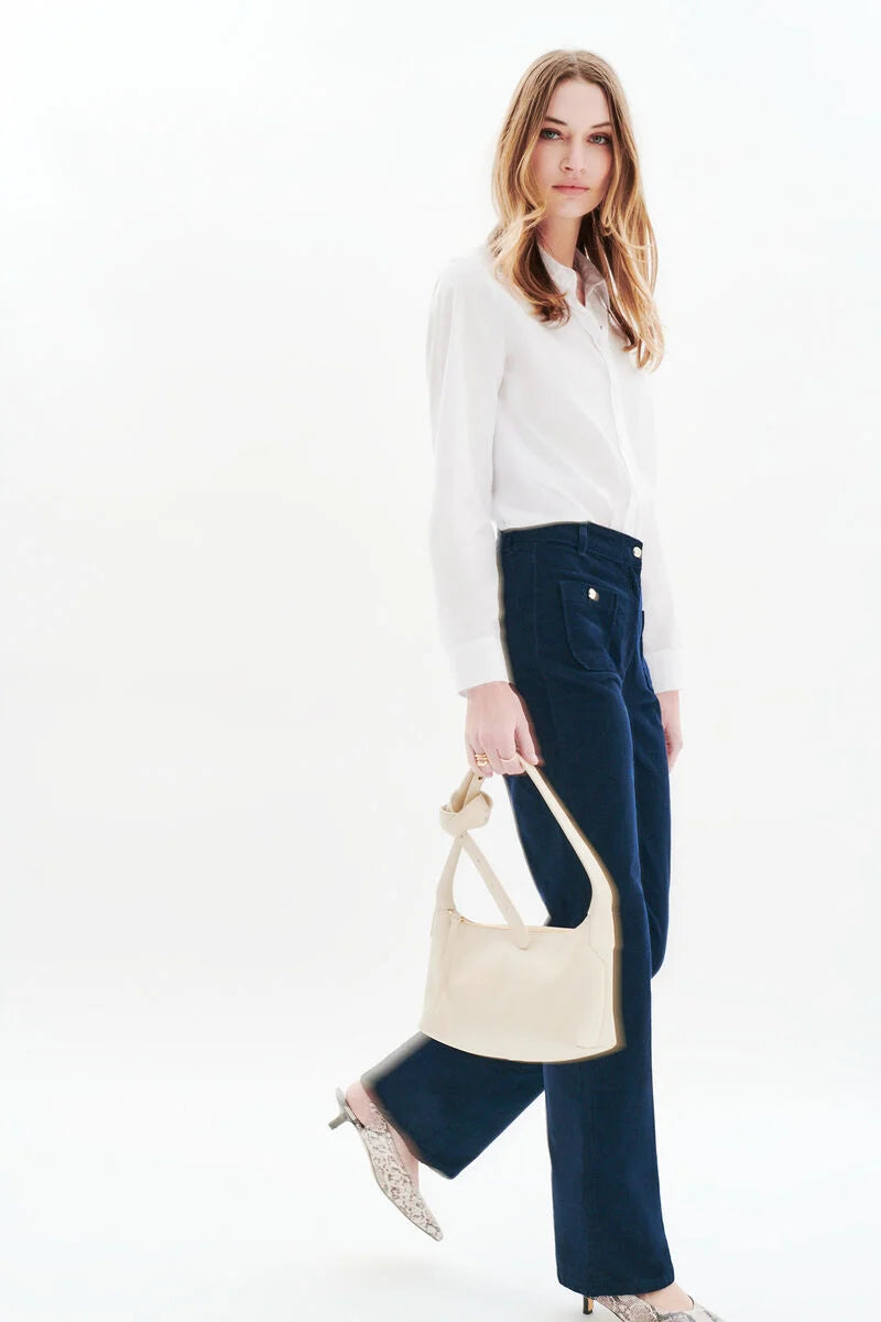 Silhouette complète avec le pantalon velours marine CAROLL Pelley, chemise blanche et sac crème