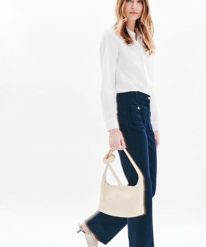 Silhouette complète avec le pantalon velours marine CAROLL Pelley, chemise blanche et sac crème