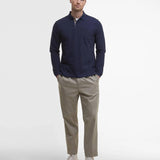 Look homme complet avec le polo manches longues bleu marine Barbour, pantalon chino beige et baskets claires