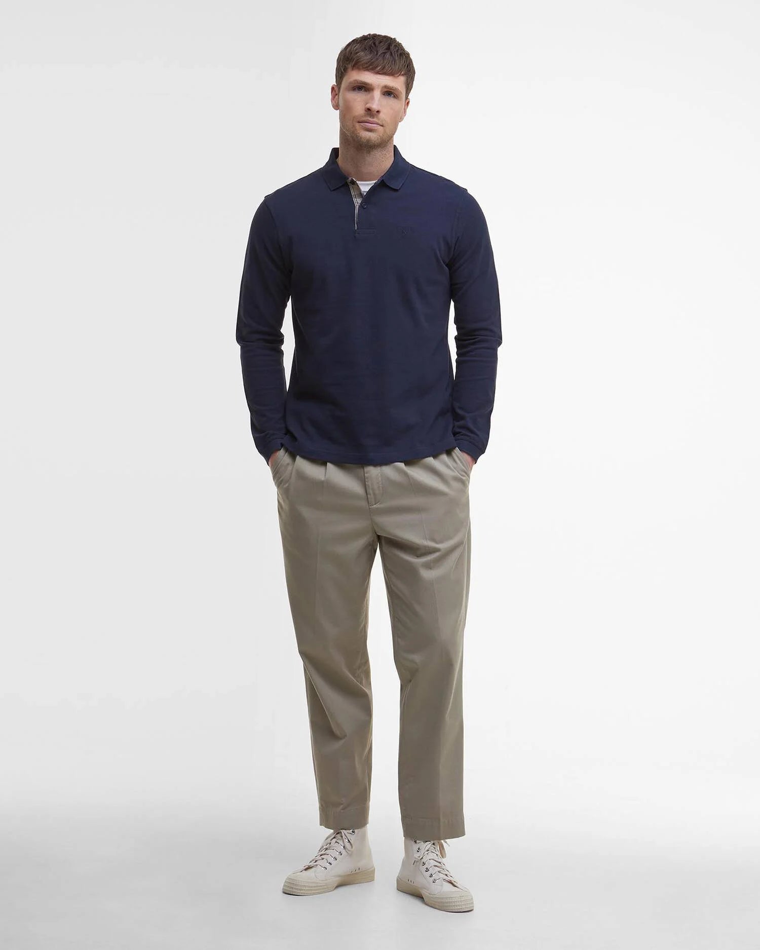 Look homme complet avec le polo manches longues bleu marine Barbour, pantalon chino beige et baskets claires