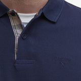 Zoom sur le col boutonné et la doublure tartan du polo bleu marine Barbour